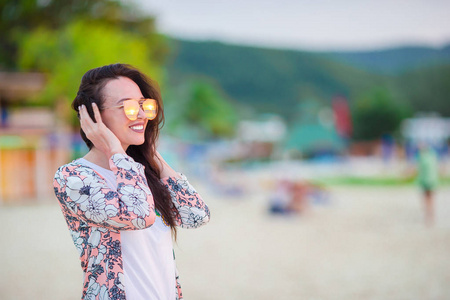 白色沙滩上的年轻美丽的女人。白种女孩在日落