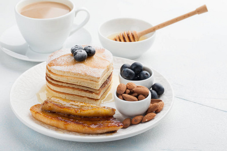 一堆美味的煎饼与蜂蜜, 咖啡和蓝莓在淡蓝色背景。情人节的丰盛早餐