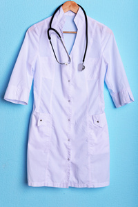 医生用听诊器在蓝色背景上的衣架上外套