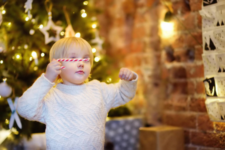 快乐的小男孩在圣诞前夜从出现的日历中取甜。儿童传统圣诞日历