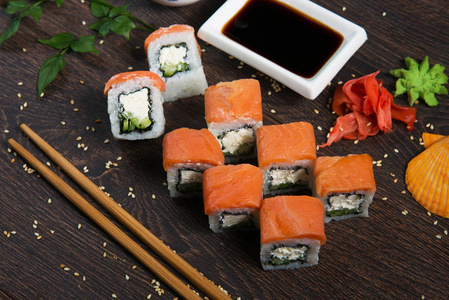 寿司卷在一家餐厅的木盘子里供应。在黑色木桌上的寿司卷和鱼子酱。日本料理