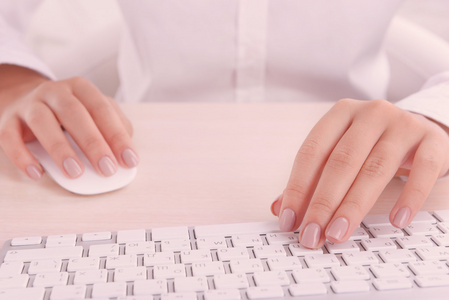 在明亮的背景上的键盘上打字的女性手