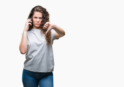 年轻的黑发女孩在智能手机上谈论孤立的背景与愤怒的脸, 显示不喜欢大拇指的负面标志, 拒绝的概念
