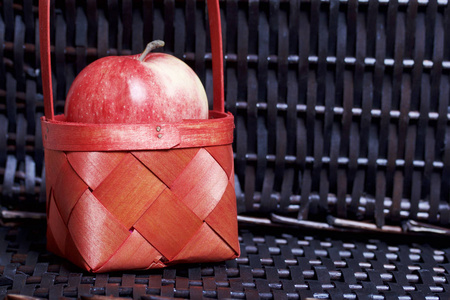 成熟的芳香苹果在一个红色柳条篮子。对柳条的柳条篮子的背景