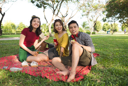 亚洲年轻人在公园里喝和吃三明治