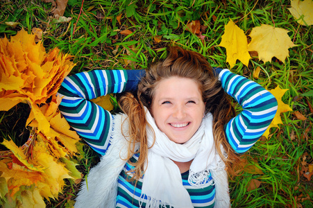 笑的女孩躺在草地上在秋天
