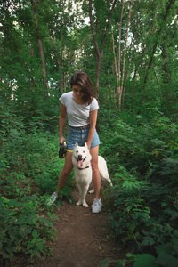 年轻的现代妇女徒步旅行与狗在夏天风景。友谊, 人, 动物