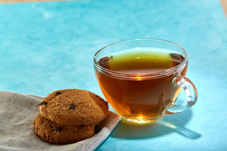 玻璃杯茶和巧克力饼干特写蓝色背景