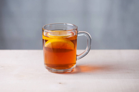 玻璃杯与茶和柠檬在灰色的背景。木材表面