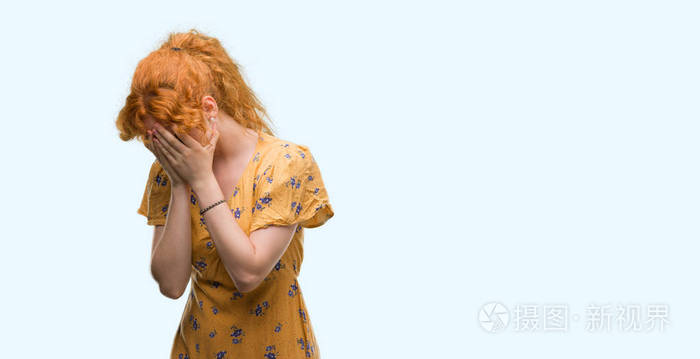 年轻的红发女人带着悲伤的表情捂着脸用手哭着.抑郁症概念