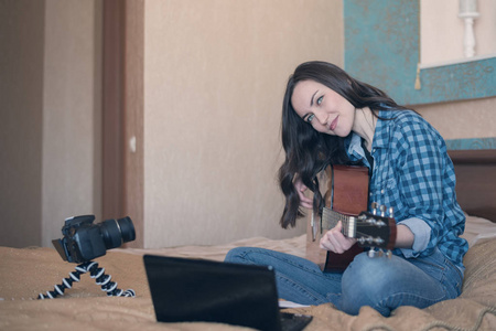 在房间里演奏声学吉他的年轻女孩