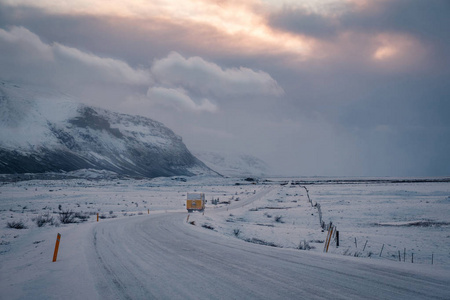 冰岛金色圆路的美丽景色和冬季景观在日落时以雪山为背景, 道路沥青为前景