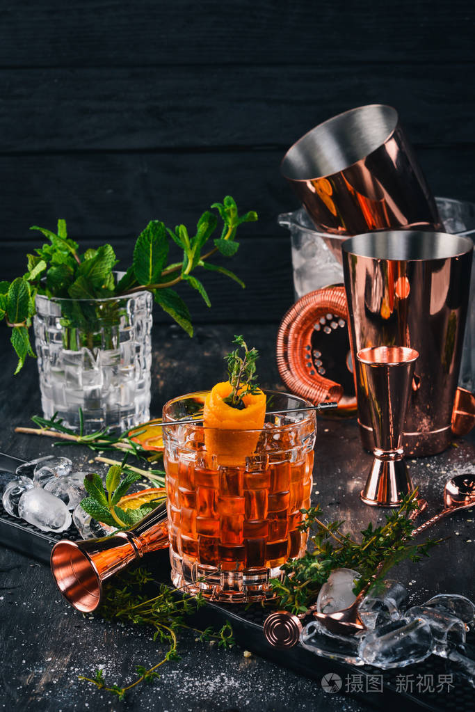酒精鸡尾酒 negroni.橘子酒冰在黑色的木质背景上