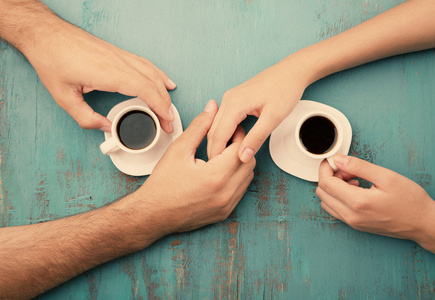 咖啡杯和在木桌上的，手牵着手