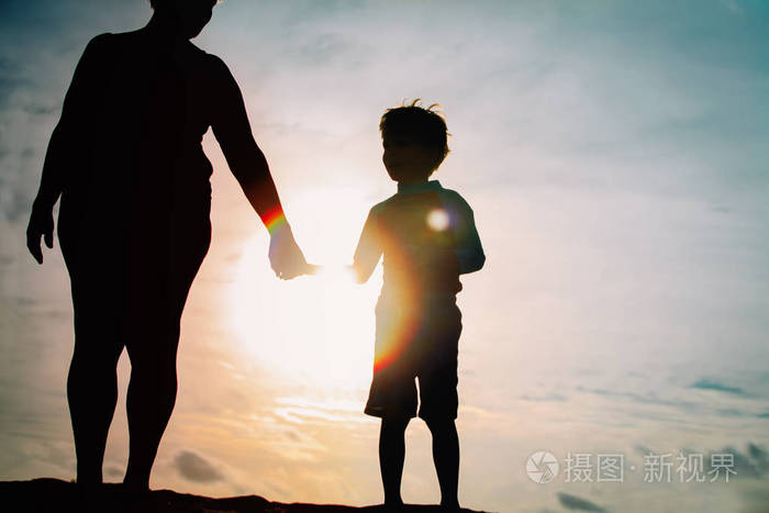 夕阳下牵手的祖母和孙子剪影