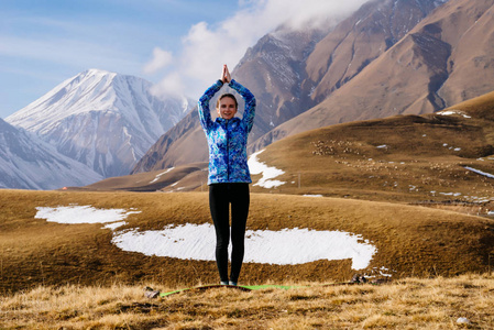 快乐的女人旅游在山的背景下练习瑜伽