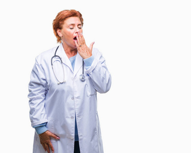 高级白种人医生妇女穿着医疗制服在孤立的背景无聊打哈欠累覆盖嘴用手。不安和嗜睡