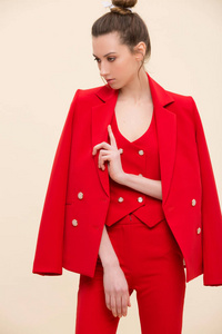 有吸引力的时装模特在红色燕尾服西装摆在工作室穿着夹克在她的肩膀上。三件西装 ponytaill 女孩竖画像