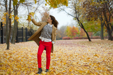 年轻女子在时尚外套秋天公园散步