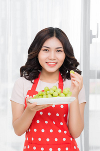 可爱的年轻女孩与绿色葡萄。健康蔬菜吃