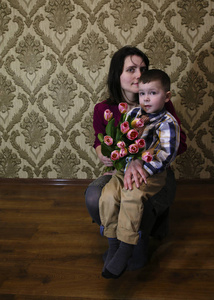 儿子祝贺他的母亲在一个女人的一天, 给她一束美丽的郁金香