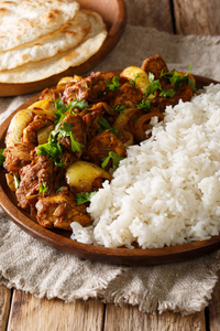 传统的印度鸡肉食谱做 pyaza dopiaza 与洋葱和香料和大米点缀在一个盘子上大饼在桌子上。vertica