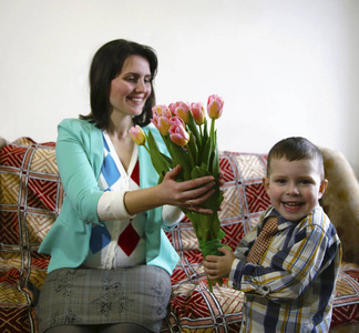 儿子祝贺他的母亲在一个女人的一天, 给她一束美丽的郁金香