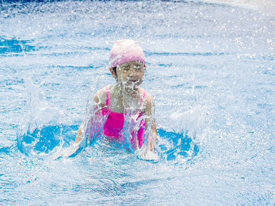 亚洲女孩在游泳池里玩, 很开心, 水溅