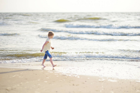 可爱的小女孩在沙滩上享受温暖和阳光明媚的夏日乐趣。在海边玩耍的孩子。儿童暑期活动