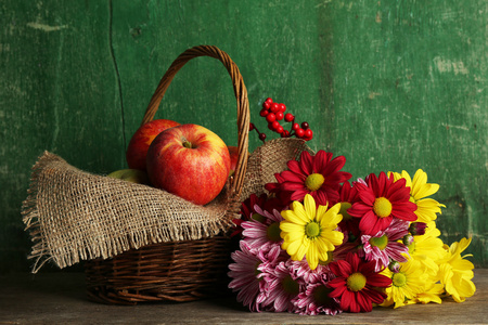 苹果在篮子里木背景上美丽菊花