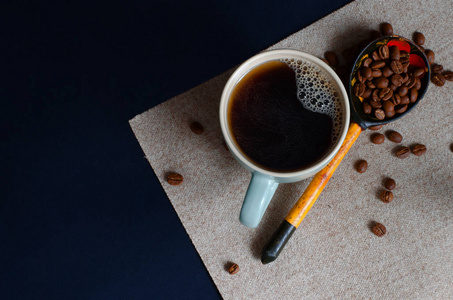 天然咖啡在杯子和咖啡豆在一个木勺在黑暗的背景。用于文本的 copyspace 图片。顶部视图