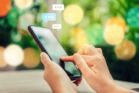 女性手使用智能手机打字, 聊天框图标聊天对话弹出。社会媒体营销技术理念。复古柔和色调背景