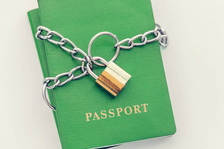 绿色护照包裹在一个蓝色的纺织品背景的黄金锁链, 特写
