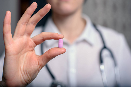 女医生拿着紫色药丸在她的手, 符号是可以的