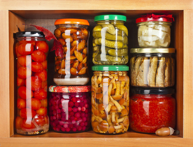 许多的玻璃瓶中孤立的白色背景上的木柜保存食物照片