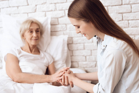 女孩照顾老人在床上的家庭和他们牵手