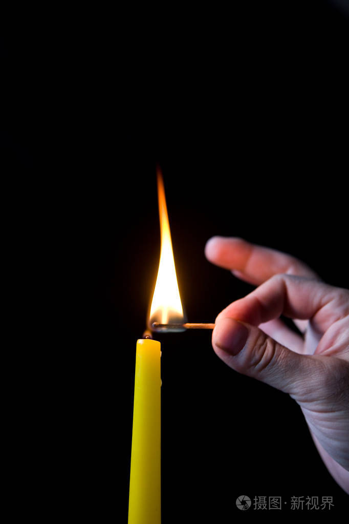 一个男人的手在黑暗中点燃一支蜡烛