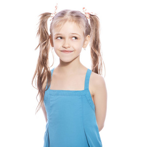 年轻的七岁的黑发女孩在蓝色礼服上的白色孤立的背景。微笑和幸福的情绪在她的脸上。女孩小姐两个门牙