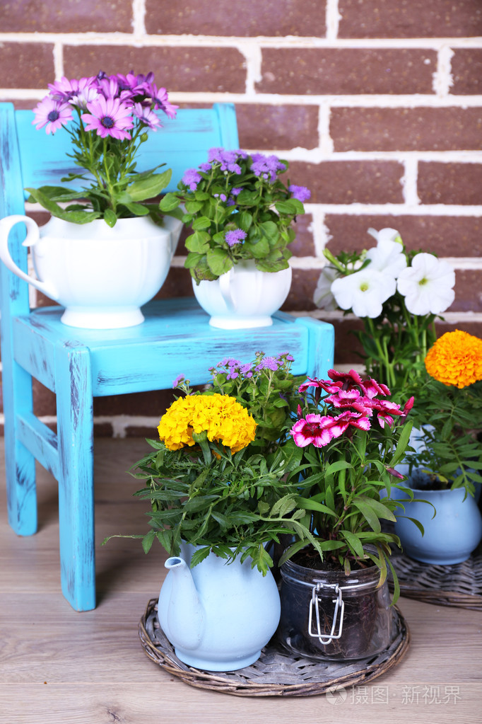 鲜花装饰花盆里种上椅子上, 在砖背景