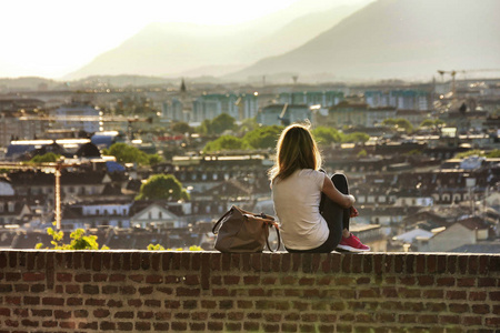 妇女单独后视图观看城市全景从山观点在阳台的砖砌体在日落都灵意大利大约2016年5月