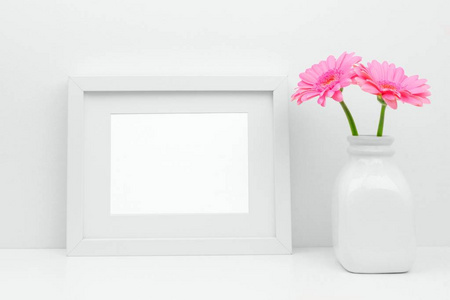 在架子或桌子上用花瓶来模拟白色框架和粉红色的菊花花。白色配色方案。横向框架方向