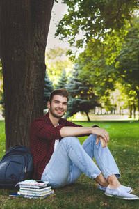 年轻英俊的男子坐在草地上的户外