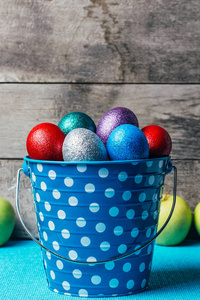 彩色复活节彩蛋在蓝色罐子桶在木背景