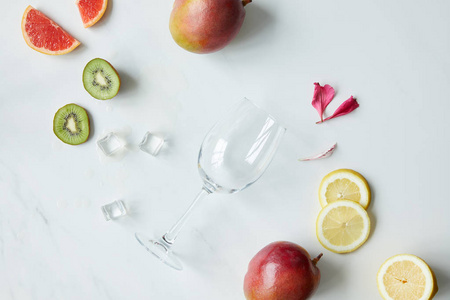 平躺与空酒杯, 花瓣, 冰块和各式各样的异国情调的水果在白色桌面上