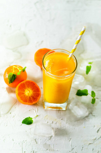 鲜橘汁在玻璃上的白色混凝土背景.橙果加冰块, 薄荷.夏季热冷饮料.