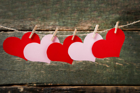 红色和粉红色的纸心挂在绳子上的木制背景