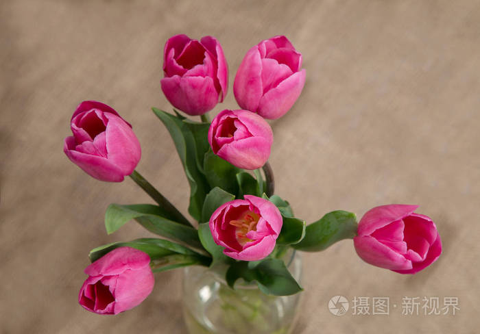 在一个粗糙的背景玻璃花瓶粉红色的新鲜郁金香花束