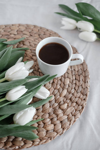 一束白色的郁金香和一杯咖啡在桌上