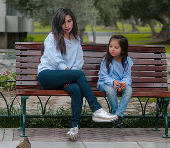 母亲和她的小女儿坐在公园的长凳上