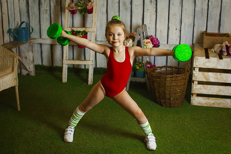 小女孩用哑铃健美运动员举哑铃小女孩控股哑铃举着手机的震惊小女孩的